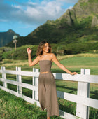 Woman wearing smocked tube top and loose pant in medium brown linen.