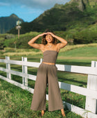 Woman wearing smocked tube top and loose pant in medium brown linen.