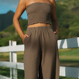 Woman wearing smocked tube top and pant in medium brown linen.