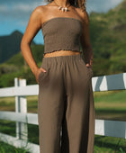 Woman wearing smocked tube top and pant in medium brown linen.