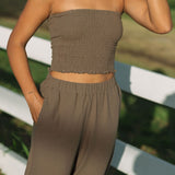Woman wearing smocked tube top and pant in medium brown linen.