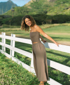 Woman wearing smocked tube top and loose pant in medium brown linen.