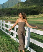 Woman wearing smocked tube top and loose pant in medium brown linen.