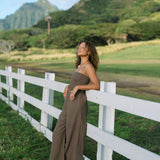 Woman wearing smocked tube top and loose pant in medium brown linen.