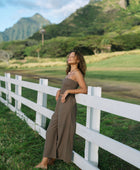 Woman wearing smocked tube top and loose pant in medium brown linen.