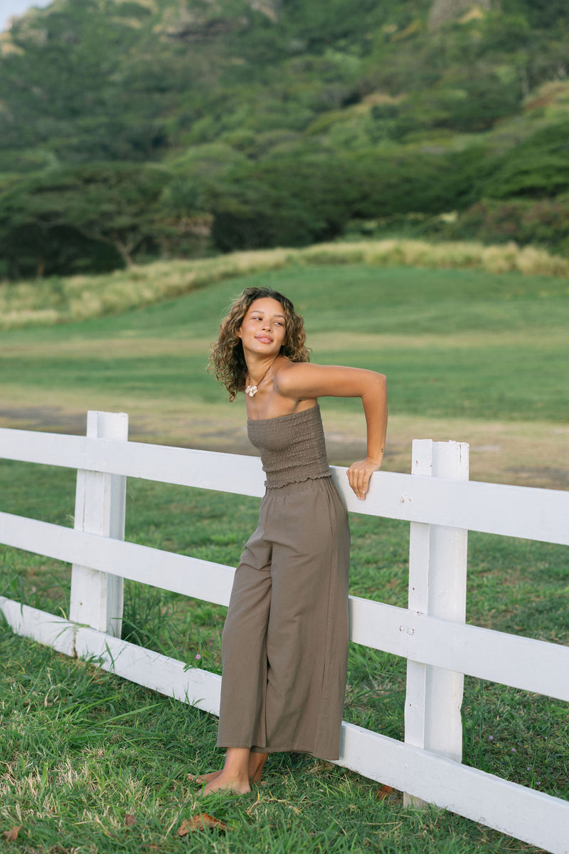 Woman wearing smocked tube top and pant in medium brown linen.