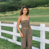 Woman wearing smocked tube top and loose pant in medium brown linen.