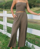 Woman wearing smocked tube top and loose pant in medium brown linen.