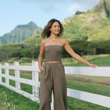 Woman wearing smocked tube top and loose pant in medium brown linen.