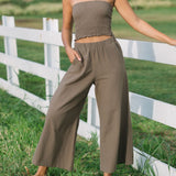 Woman wearing smocked tube top and loose pant in medium brown linen.