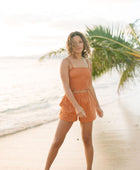 Woman wearing burnt orange linen smocked tube top with spaghetti straps and short.