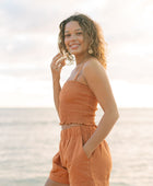 Woman wearing burnt orange linen smocked tube top with spaghetti straps and short.