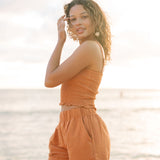 Woman wearing burnt orange linen smocked tube top with spaghetti straps and short.