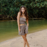Woman wearing smocked tube top with spaghetti straps and short in medium brown linen.
