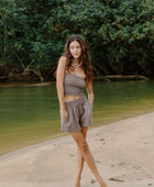 Woman wearing smocked tube top with spaghetti straps and short in medium brown linen.