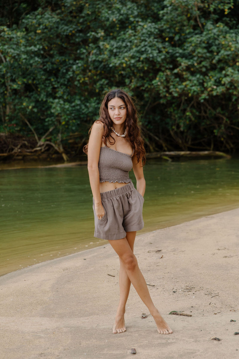 Woman wearing smocked tube top with spaghetti straps and short in medium brown linen.