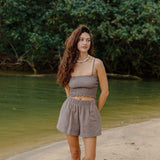 Woman wearing smocked tube top with spaghetti straps and short in medium brown linen.
