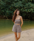 Woman wearing smocked tube top with spaghetti straps and short in medium brown linen.