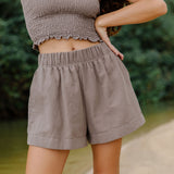 Woman wearing smocked tube top with spaghetti straps and short in medium brown linen.