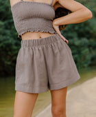 Woman wearing smocked tube top with spaghetti straps and short in medium brown linen.