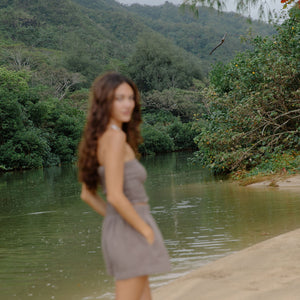 Woman wearing smocked tube top with spaghetti straps and short in medium brown linen.