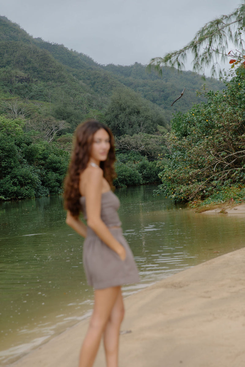 Woman wearing smocked tube top with spaghetti straps and short in medium brown linen.