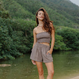 Woman wearing smocked tube top and short in medium brown linen.