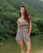 Woman wearing smocked tube top and short in medium brown linen.