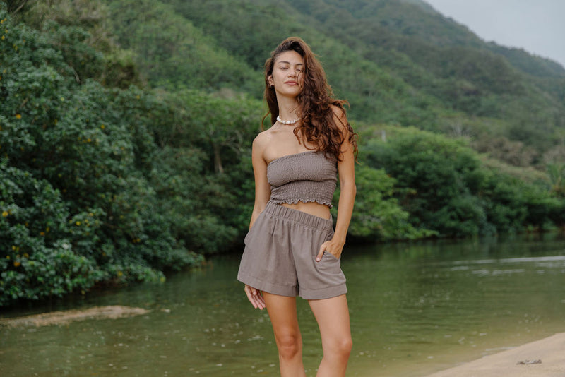 Woman wearing smocked tube top and short in medium brown linen.