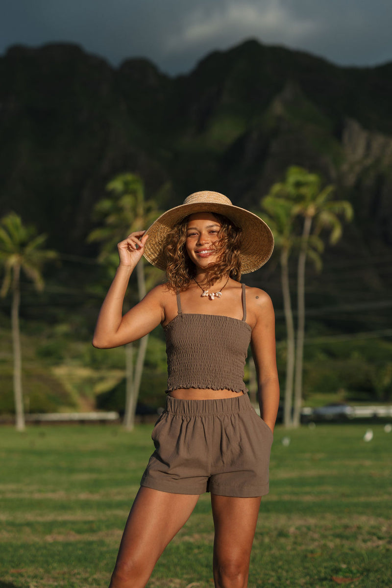 Woman wearing smocked tube top with spaghetti straps and short in medium brown linen.