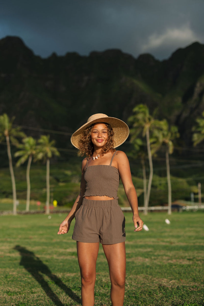 Woman wearing smocked tube top with spaghetti straps and short in medium brown linen.