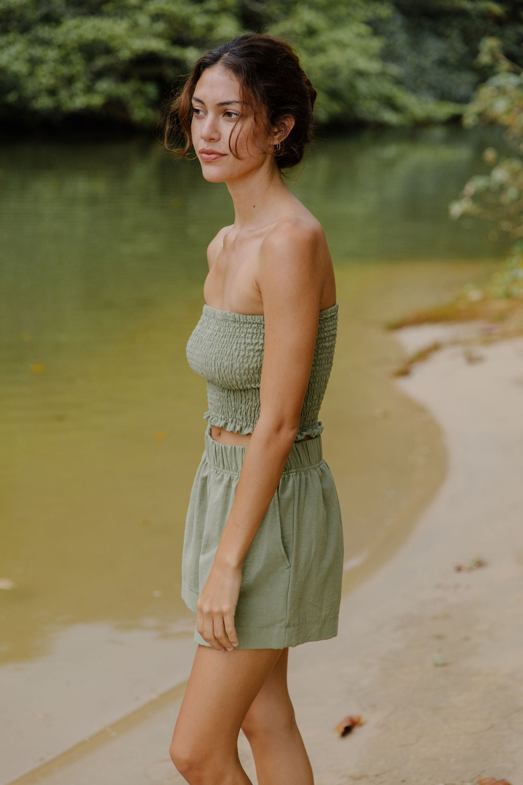 Woman wearing smocked tube top and short in medium green linen.