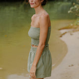 Woman wearing smocked tube top and short in medium green linen.