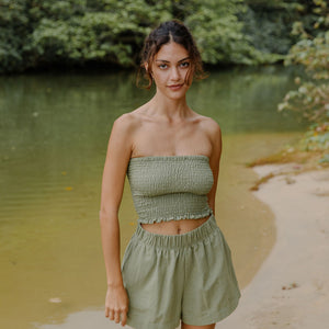 Woman wearing smocked tube top and short in medium green linen.