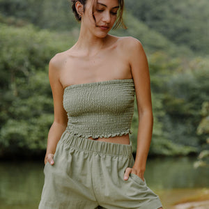 Woman wearing smocked tube top and short in medium green linen.