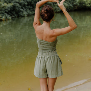 Woman wearing smocked tube top and short in medium green linen.