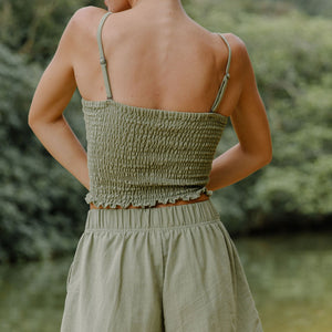 Woman wearing smocked tube top with spaghetti straps and short in medium green linen.