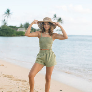 Woman wearing smocked tube top with spaghetti straps and short in medium green linen.