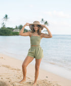 Woman wearing smocked tube top with spaghetti straps and short in medium green linen.