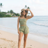 Woman wearing smocked tube top with spaghetti straps and short in medium green linen.