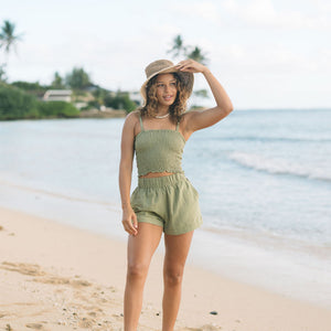 Woman wearing smocked tube top with spaghetti straps and short in medium green linen.