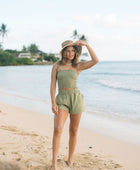 Woman wearing smocked tube top with spaghetti straps and short in medium green linen.