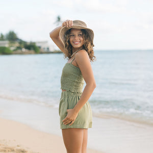 Woman wearing smocked tube top with spaghetti straps and short in medium green linen.
