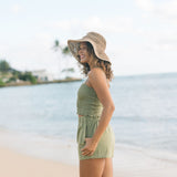 Woman wearing smocked tube top with spaghetti straps and short in medium green linen.