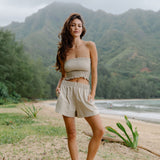 Woman wearing smocked beige linen tube top and short.