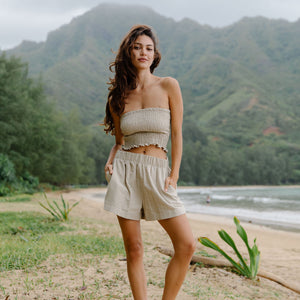 Woman wearing smocked beige linen tube top and short.
