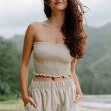 Woman wearing smocked beige linen tube top and short.