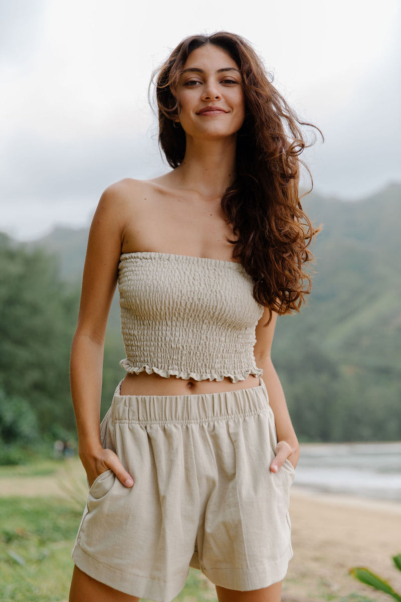 Woman wearing smocked beige linen tube top and short.