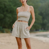 Woman wearing smocked beige linen tube top with spaghetti straps and short.