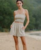 Woman wearing smocked beige linen tube top with spaghetti straps and short.